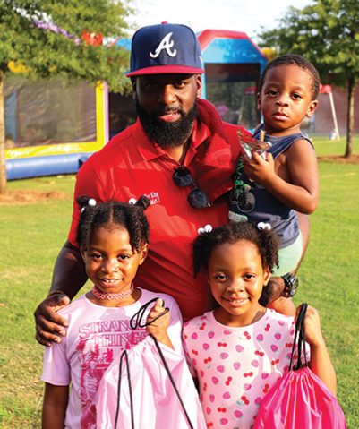 Councilman Cleo King poses with kids from backpack giveaway event